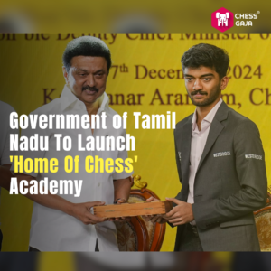 Two individuals stand on a stage. One person is presenting a wooden plaque to the other. Text reads, "Government of Tamil Nadu To Launch 'Home Of Chess' Academy.
