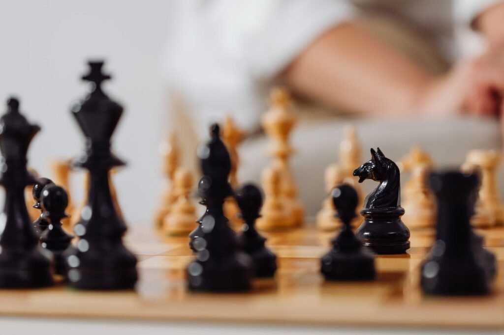 Black chess pieces in the foreground with a player blurred in the background, representing the Caro-Kann Defense opening for Black