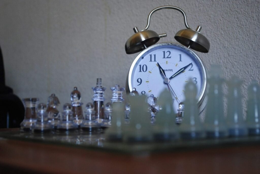 An alarm clock sitting behind chess pieces on a board, representing time pressure in chess tournaments